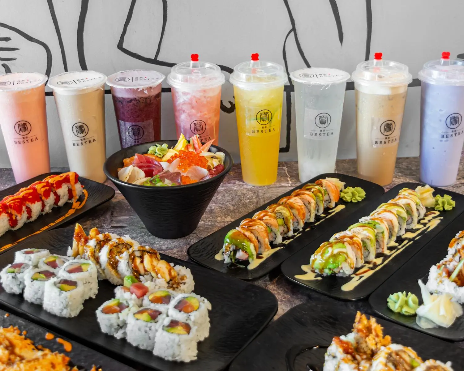 A variety of Japanese sushi and colorful BESTEA beverages are displayed, creating an appetizing scene.